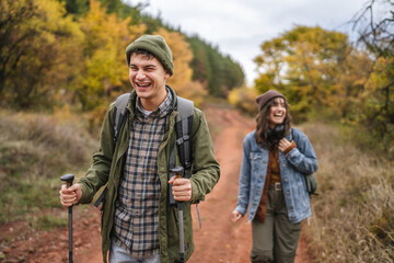 Smiling couple hiking forest trail during autumn