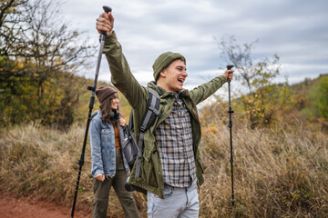 Teenager hiking with trekking poles on nature trail expressing joy