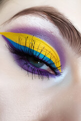 Kolorowy makijaż oka w odcieniach żółci, niebieskiego i fioletu – kreatywny beauty trend i artystyczna stylizacja
