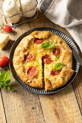 Crispy tomato galette with adyghe cheese and herbs on rustic background. Copy space.