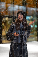 Happy female standing in the snowfall at the city