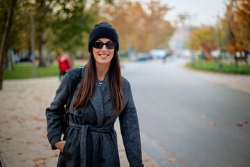 Smiling middle-aged woman wearing scarf and beanie in a park during the autumn season