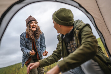 Happy couple laughing inside camping tent outdoors