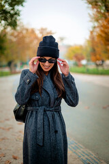 Smiling middle-aged woman wearing scarf and beanie in a park during the autumn season