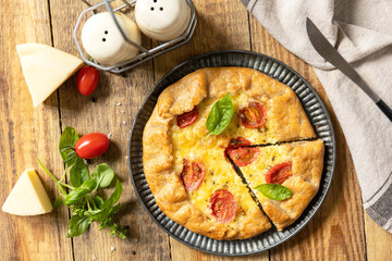 Crispy tomato galette with adyghe cheese and herbs on rustic background. Top view.