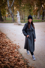 Smiling middle-aged woman wearing scarf and beanie in a park during the autumn season