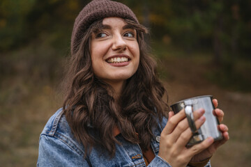 Young woman enjoying warm drink in autumn forest