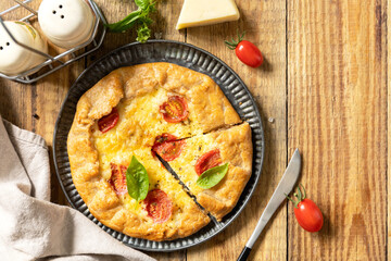 Crispy tomato galette with adyghe cheese and herbs on rustic background. Top view.