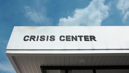 Crisis Center word sign displayed on the exterior of a building under a clear blue sky, symbolizing emergency response, support services, mental health assistance, and community crisis management.
