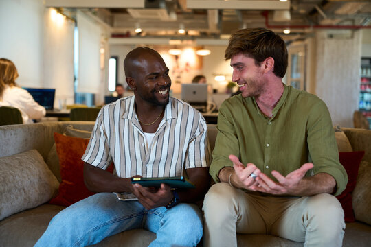 Diverse men colleagues talking smiling in modern office