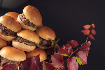 Mini beef sliders stacked on a glass stand with autumn leaves