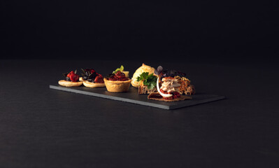 Top-down arrangement of gourmet bites on dark slate