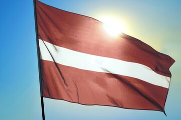 Latvia national flag waving in sunlight close-up &ndash; Latvian carmine red banner with white horizontal stripe patriotic Baltic country symbol background blue sky bright sunny day