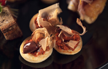 Gourmet blinis with tomato spread, olives and bonito flakes