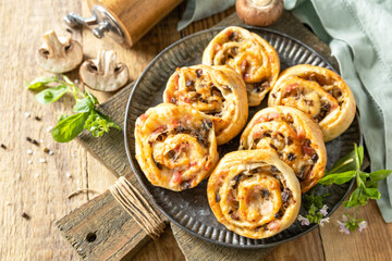 Puff pastry rolls with mushroom and cheese filling on rustic background.