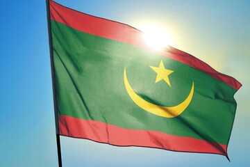 Mauritania national flag waving in sunlight close-up &ndash; Mauritanian green banner with red stripes yellow crescent and star patriotic West African country background blue sky bright sunny day