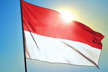 Monaco national flag waving in sunlight close-up &ndash; Monegasque red and white horizontal stripes banner fabric patriotic background blue sky bright sunny day high resolution tricolor symbol of monarchy