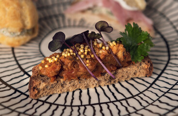 Gourmet toast with vegetable spread and microgreens on patterned plate