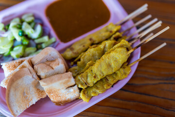 Thai satay skewers with grilled pork served with toasted bread and dipping sauces served on pink plate, Thai food style