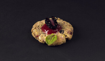 Single gourmet cookie with blackberry topping on dark background
