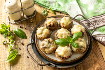 Stuffed mushrooms baked with cheese on rustic background.