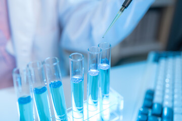 A chemistry researcher in a laboratory surrounded by scientific equipment and test tubes,...