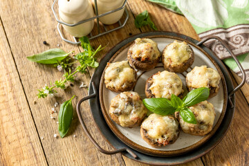 Stuffed mushrooms baked with cheese on rustic background. Copy space.