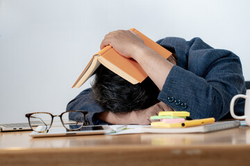 Tired young office employee fell asleep at his desk surrounded by a pile of documents and a laptop. Concept of overwork, job stress, and modern corporate burnout.