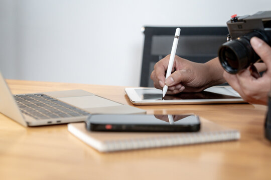 A young male photographer working from home, editing photos on a computer using professional software. Creative freelance lifestyle concept in a cozy and modern home office.