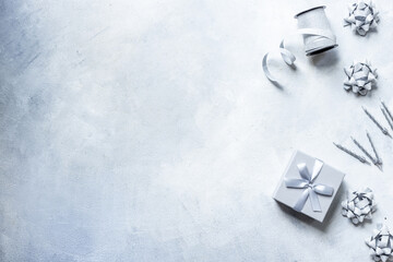 Shiny party silver streamers with confetti and cones on gray stone background, top view