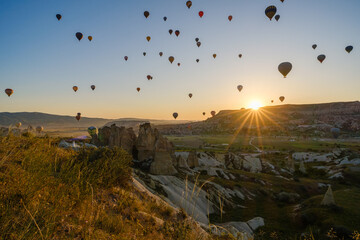 Cappadocia, Turkey - May 5 2025: Many colorful hot air balloons fly in the sky over a mountain...