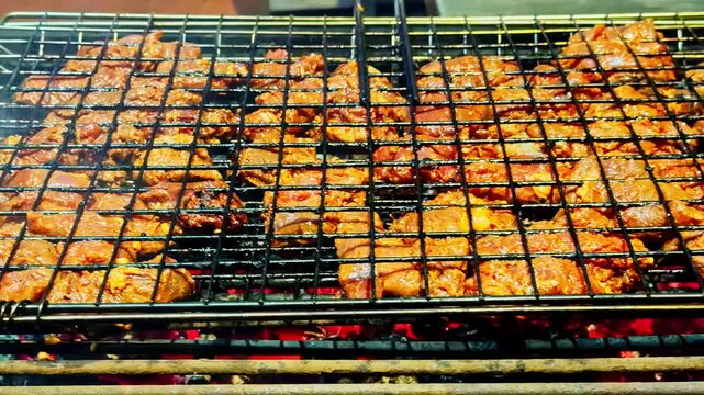 Grilled kebabs cooking on skewers in double sided grill at Sharm El Sheikh night market