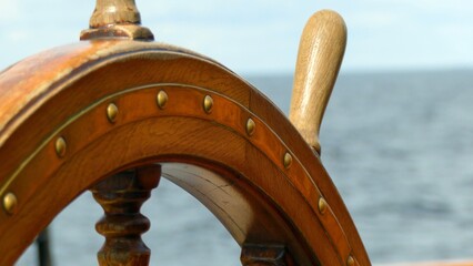 an antique ship's steering wheel against the sea