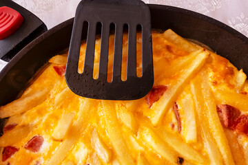 Country omelette with potatoes, tomatoes and sausage in a frying pan. Breakfast.