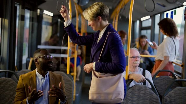 Multicultural business colleagues commuting and conversing together on a public bus, sharing a friendly moment during their daily journey to work among other diverse passengers