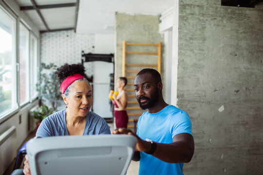 Young fitness instructor working with a senior female client in a gym - Powered by Adobe