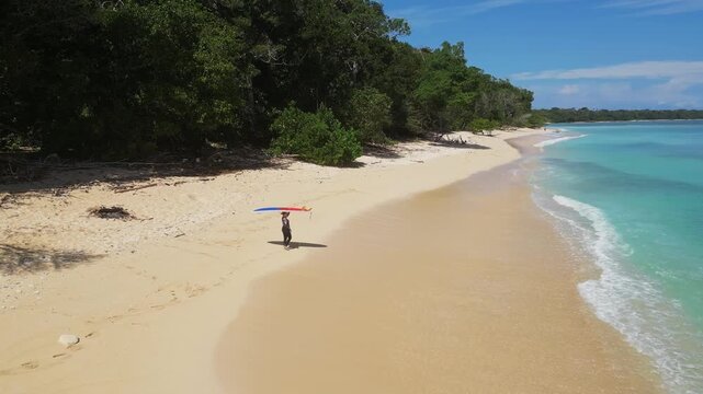 Drone perspective capturing peaceful tropical beach with lonely female surfer,G-Land, Plengkung Beach, Grajagan Bay, Banyuwangi, Alas Purwo National Park, East Java