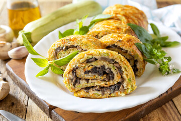 Zucchini roll with mushroom filling and herbs served on a white plate on a rustic table.