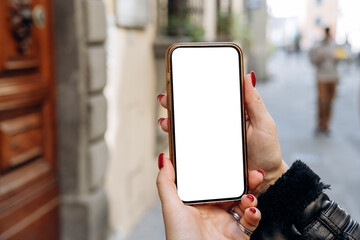 Mockup woman's hand holding using smart phone, Hands are holding a smartphone featuring a blank screen, positioned in front of a wooden door, real estate rent, mobile app design and advertising