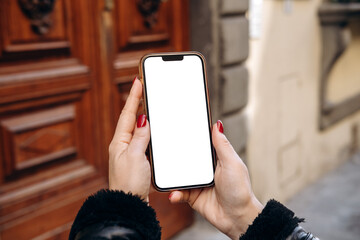 Mockup woman's hand holding using smart phone, Hands are holding a smartphone featuring a blank screen, positioned in front of a wooden door, real estate rent, mobile app design and advertising