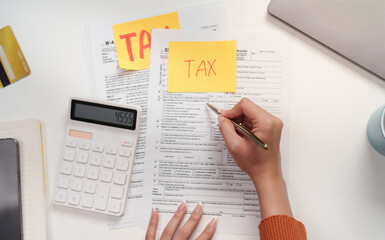 Tax filing. Individual completing tax forms with a calculator and paperwork.