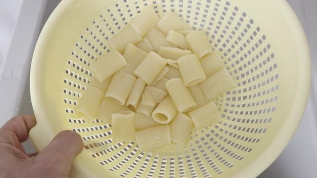 Draining Cooked Pasta into a Colander in Kitchen Sink