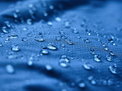 Water drops on waterproof membrane fabric. Detail view of texture of blue waterproof cloth.