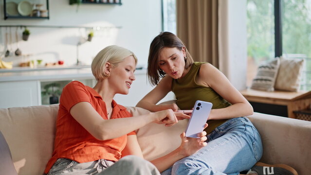 Two sisters shopping online at weekend closeup. Happy girlfriends sitting sofa