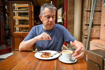 A man enjoying coffee and a pastry at a local café in Seville. 