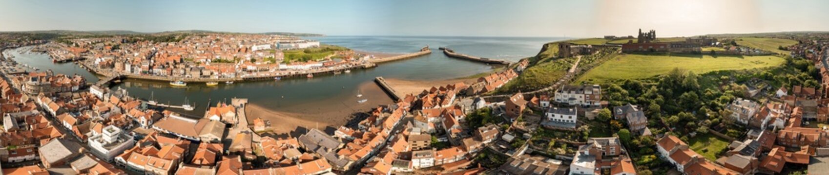 Aerial extremely wide panoramic photo of the town of Whitby in Yorkshire northern England showing the historic British seaside town and the 99 steps leading from the town to the Whitby Abbey ruins