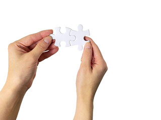 Hands connecting two white jigsaw puzzle pieces together