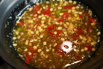 A macro, high-angle close-up of a dark bowl filled with a clear, brown, spicy Thai Seafood Sauce