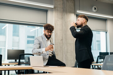 Diverse business colleagues drinking coffee discussing in office