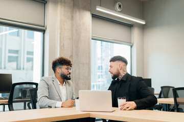 Diverse businessmen discussing work while collaborating in office
